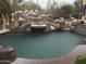 Backyard pool features custom rock waterfall, slide and lush landscaping at 6432 E Old Paint Trl, Carefree, AZ 85377