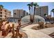 Community pool with a unique enclosed structure, palm trees, desert landscaping, and decorative metal cactus at 7830 E Camelback Rd # 108, Scottsdale, AZ 85251