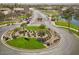 Aerial view of the community entrance showing a roundabout with mature landscaping, a gate, and a pond at 856 E Indian Wells Pl, Chandler, AZ 85249