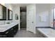 Modern bathroom with double sinks, a soaking tub with decorative tile, and glass shower at 9214 N 83Rd St, Scottsdale, AZ 85258