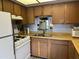 Well-lit kitchen with wooden cabinetry, white appliances, and sink with view mirror at 925 E Lancaster Cir, Florence, AZ 85132