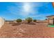 Wide backyard space landscaped with desert rock and some mature trees, enclosed by a block fence at 9283 W Rafael Dr, Arizona City, AZ 85123