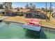 Waterfront home featuring a boat dock and a red and white pontoon boat on a canal at 10116 W Bolivar Dr, Sun City, AZ 85351