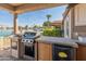Outdoor kitchen featuring stainless steel grill, mini fridge, and bar with view of lake at 10116 W Bolivar Dr, Sun City, AZ 85351