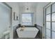 Bright bathroom featuring a modern soaking tub, decorative lighting and tiled floors at 1414 E Amberwood Dr, Phoenix, AZ 85048
