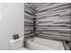 Modern bathroom featuring stylish gray tiling, a bathtub, and neutral walls at 1625 S 113Th Ave, Avondale, AZ 85323