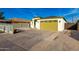 Side view of a single-story home featuring a long driveway, gravel landscaping, and yellow two-car garage at 1625 S 113Th Ave, Avondale, AZ 85323