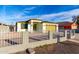Street view of a single-story home featuring a white picket fence, gravel landscaping, and a yellow two-car garage at 1625 S 113Th Ave, Avondale, AZ 85323