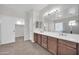 Bathroom with dual sinks, wood cabinets, large mirror, and walk-in closet at 17388 W Elaine Dr, Goodyear, AZ 85338