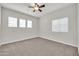 Neutral bedroom features carpet, ceiling fan, and natural light from large windows at 17388 W Elaine Dr, Goodyear, AZ 85338
