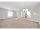 Open living room featuring neutral carpet, a ceiling fan, and a chandelier at 17388 W Elaine Dr, Goodyear, AZ 85338