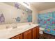 Bright bathroom with a double sink vanity, decorative mirror, and a cheerful shower curtain at 17722 N 183Rd Ave, Surprise, AZ 85374