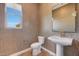 Chic powder room boasts geometric wallpaper, pedestal sink, and a window providing natural light at 18429 W Mohave St, Goodyear, AZ 85338
