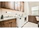 Functional laundry room with dark wood cabinets, granite countertops, and modern washer and dryer units at 19140 N 259Th Ave, Buckeye, AZ 85396