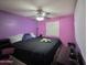 Bedroom showing purple walls, ceiling fan, and bed with black bedding at 2019 N 78Th Ave, Phoenix, AZ 85035