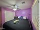 This bedroom features purple walls, a ceiling fan, and a comfortable bed at 2019 N 78Th Ave, Phoenix, AZ 85035