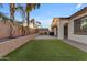 Lush backyard featuring artificial grass, palm trees, and a built-in barbecue at 22837 E Silver Creek Ln, Queen Creek, AZ 85142