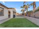 Large backyard featuring artificial turf, palm trees, and a stone retaining wall at 22837 E Silver Creek Ln, Queen Creek, AZ 85142