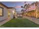 Expansive backyard featuring a lush lawn, patio area, palm trees, and privacy wall, creating a serene outdoor retreat at 22837 E Silver Creek Ln, Queen Creek, AZ 85142