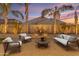 Inviting backyard patio with comfortable seating, lush palm trees, and a charming water feature perfect for outdoor relaxation at 22837 E Silver Creek Ln, Queen Creek, AZ 85142