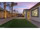 Well-manicured backyard featuring an artificial grass lawn, palm trees, and a paved patio perfect for entertaining at 22837 E Silver Creek Ln, Queen Creek, AZ 85142