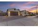 Attractive single-Gathering home featuring a two-car garage, desert landscaping, and a paved driveway at dusk at 22837 E Silver Creek Ln, Queen Creek, AZ 85142