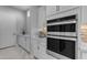 Gourmet kitchen boasts stainless steel built-in double ovens, white cabinets, marble countertops and backsplash at 22837 E Silver Creek Ln, Queen Creek, AZ 85142