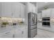 Bright kitchen featuring stainless steel refrigerator, white cabinetry, tile backsplash, and marble countertops at 22837 E Silver Creek Ln, Queen Creek, AZ 85142