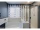 Bathroom featuring a white bathtub with a shower and a patterned curtained window at 2527 W Amber Sun Dr, Phoenix, AZ 85085