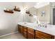 Bathroom features a dual sink vanity with wood cabinets, a large mirror, and decorative shelving at 26826 N 66Th Ln, Phoenix, AZ 85083