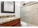 Bathroom featuring granite vanity, framed mirror, and a glass shower door with beige tile at 3241 E Granada Rd, Phoenix, AZ 85008