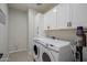 A lovely laundry room that has modern washer and dryer, white cabinets, dark hardware, and a clean aesthetic at 35307 N Agua Caliente --, San Tan Valley, AZ 85144