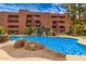 Beautiful community pool with an artificial waterfall near a multi-story building and lush trees at 4303 E Cactus Rd # 408, Phoenix, AZ 85032