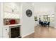 Stylish bar area featuring a wine fridge, glass shelving, and view into the dining area at 5456 E Woodridge Dr, Scottsdale, AZ 85254