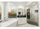 Bright bathroom featuring a modern chandelier, soaking tub, black countertops, and a walk-in shower with herringbone tile at 5456 E Woodridge Dr, Scottsdale, AZ 85254