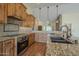 Kitchen with a stone backsplash, wooden cabinetry, and stainless steel appliances in an open-concept design at 6010 E Greenway Ln, Scottsdale, AZ 85254