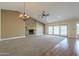 Cozy living room with stone fireplace, chandelier, ceiling fan, and sliding glass doors to the backyard at 6010 E Greenway Ln, Scottsdale, AZ 85254