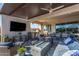 Spacious covered patio with an outdoor kitchen, dining area, comfortable lounge seating, and a fire pit at 9183 W Foothill Dr, Peoria, AZ 85383
