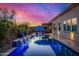 Backyard oasis featuring a sparkling pool, cascading water feature, umbrella covered lounge chairs, and festive string lights at 9183 W Foothill Dr, Peoria, AZ 85383