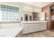 Bright bathroom featuring a soaking tub with a mosaic accent wall and dual sink vanity at 11265 E Laguna Azul Cir, Mesa, AZ 85209