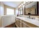 Bright bathroom featuring a walk-in tub and double sink vanity with decorative cabinets and mirrors at 12622 W Avalon Dr, Avondale, AZ 85392