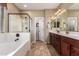 Bright bathroom featuring a soaking tub, glass enclosed shower, and double vanity at 13108 N 91St N Ln, Peoria, AZ 85381