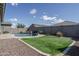 Fully landscaped backyard featuring travertine tile, turf, pool, and waterfall at 15233 W Baden St, Goodyear, AZ 85338