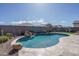 Beautiful backyard pool with rock waterfall feature, tiki torches, and lush landscaping for relaxation and fun at 15233 W Baden St, Goodyear, AZ 85338