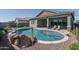 Backyard pool featuring rock accents, baja step, and travertine tile at 15233 W Baden St, Goodyear, AZ 85338