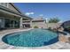 Backyard pool with travertine tile, waterfall, and covered patio at 15233 W Baden St, Goodyear, AZ 85338