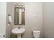 Elegant powder room with pedestal sink, framed mirror, and neutral tones, offers a convenient space for guests at 15233 W Baden St, Goodyear, AZ 85338