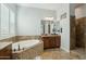 Bathroom featuring dual sinks, tiled floors, and a corner soaking tub and shower at 15837 W Bonitos Dr, Goodyear, AZ 85395