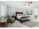 Bright main bedroom featuring a ceiling fan, tray ceiling, and comfortable seating area at 15837 W Bonitos Dr, Goodyear, AZ 85395