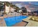 Twilight image of the backyard featuring a pool with in-ground lighting and a waterfall feature at 15837 W Bonitos Dr, Goodyear, AZ 85395